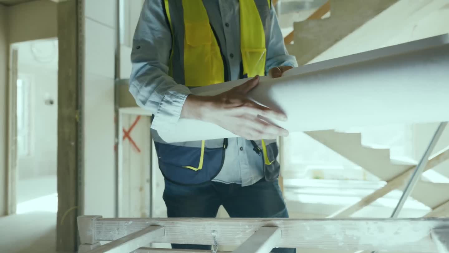 Bauleiter rollt Pläne auf der Baustelle aus